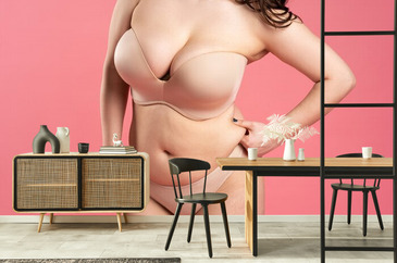 Fat Woman with Large Breasts in a Push-up Bra on Pink Background