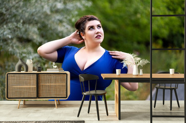 Sexy plus size model in blue dress with a deep neckline outdoors