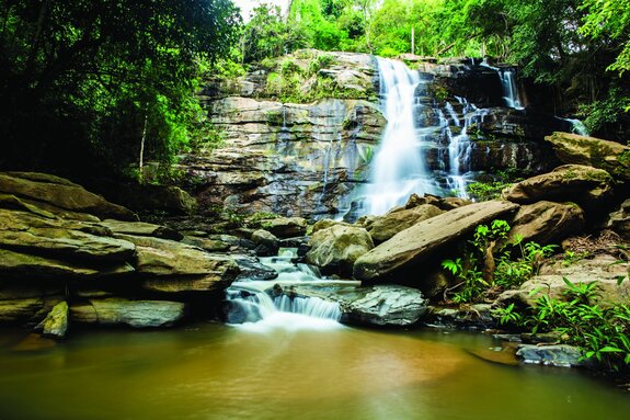 Natürliche landschaft wasserfall zwischen steinen und bäumen