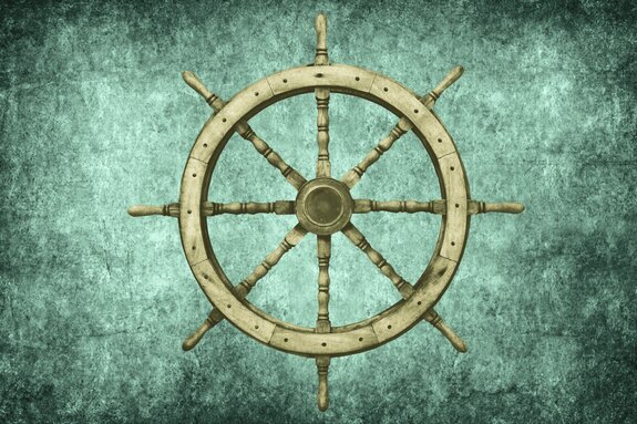 Holzsteuerrad eines schiffes vor einem betonhintergrund