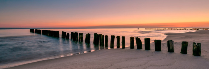 Holzpfähle an einem sandigen meeresstrand