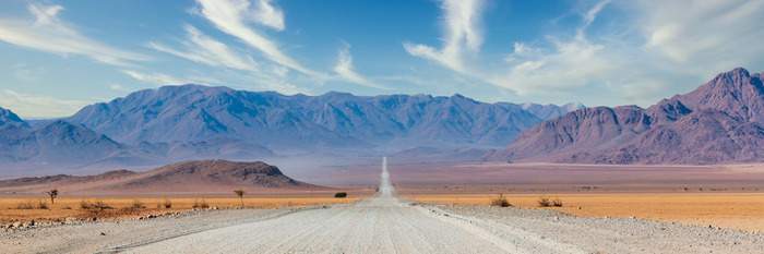 Eine gerade straße in richtung der berge in einem wüstental