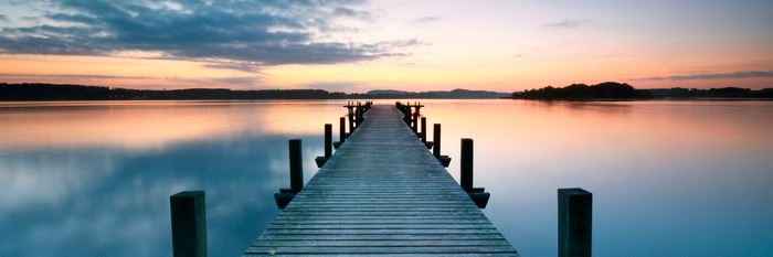 Ein steg auf einem ruhigen see bei sonnenuntergang