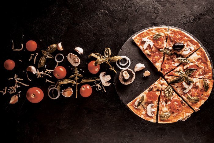 Pizza mit gemüse und basilikumblättern