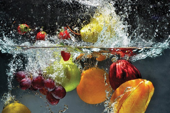 Bunte früchte fallen dynamisch ins wasser