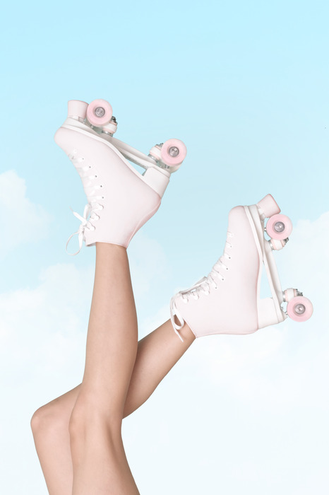 Weiße rollschuhe an füßen vor blauem himmel