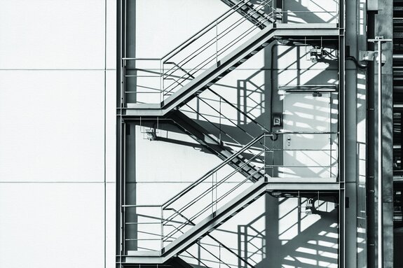 Escalier métallique extérieur sur un mur blanc