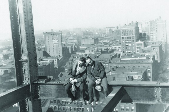 Hommes sur une structure métallique sur fond de ville