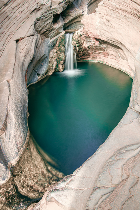 Une cascade se jetant dans un bassin turquoise creusé dans les rochers