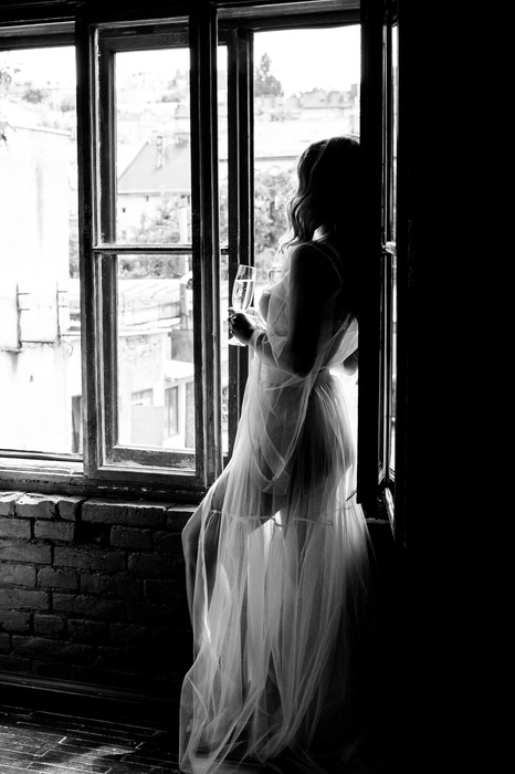 Une femme en robe près d'une fenêtre en noir et blanc