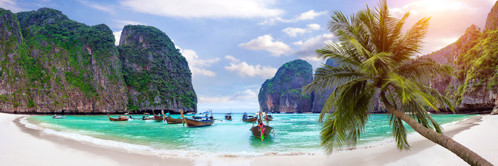 Plage tropicale et bateaux entourés de falaises