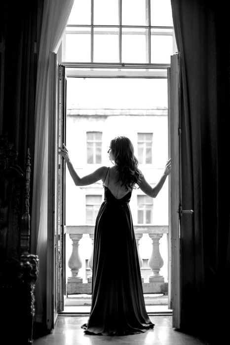 Une femme en robe longue à la fenêtre du balcon