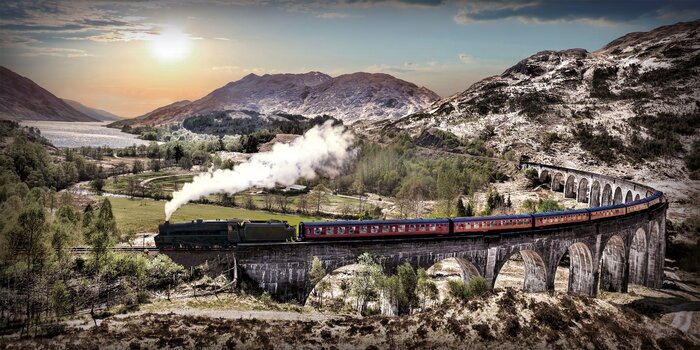 Un train au milieu des montagnes et des lacs au coucher du soleil