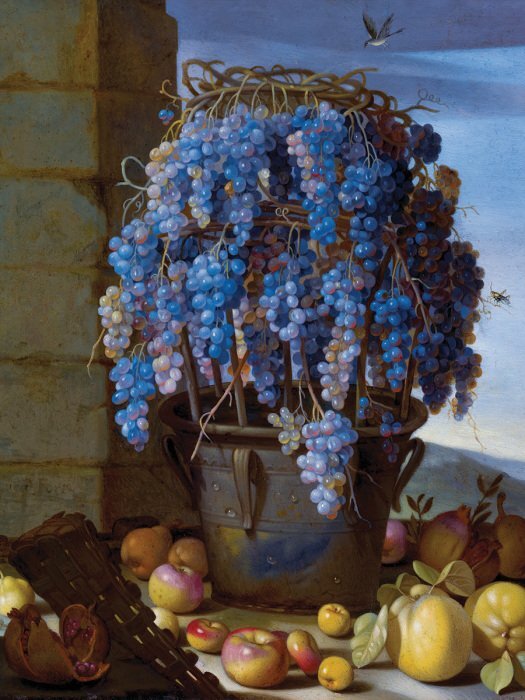 Un seau en métal rempli de raisins entouré de pommes