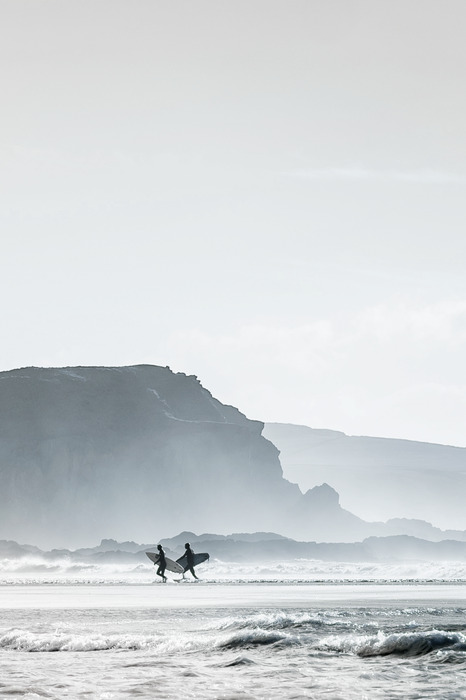 Des surfeurs avec leurs planches sur une plage bordée d'une falaise