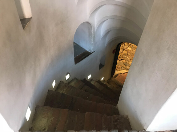 Steep stone spiral stairs going down from the steps