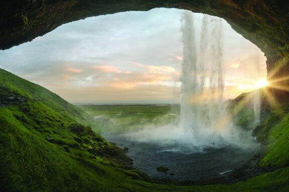 Uitzicht vanuit de grot op een natuurlijk landschap met een waterval