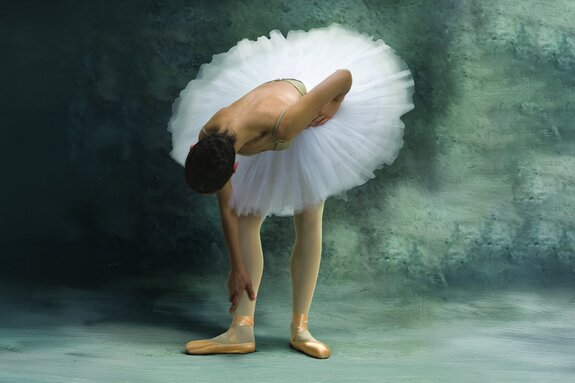 Een ballerina in een lichte rok tegen een betonnen achtergrond