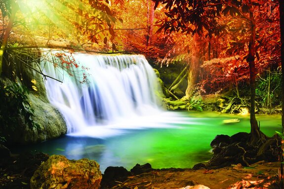 Landschap van zonnestralen over een waterval in de herfst