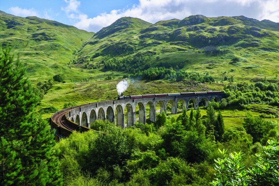Een trein rijdt over een brug in een bergachtig landschap