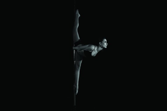 Een vrouw die de split doet tijdens een paaldans