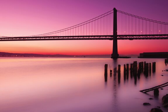 Landschap met een zonsondergang en een brug tegen een roze lucht