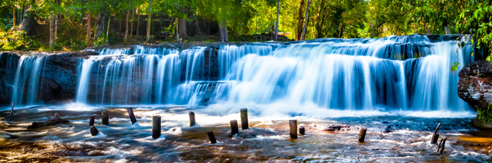 Brede blauwe waterval in een dicht bos