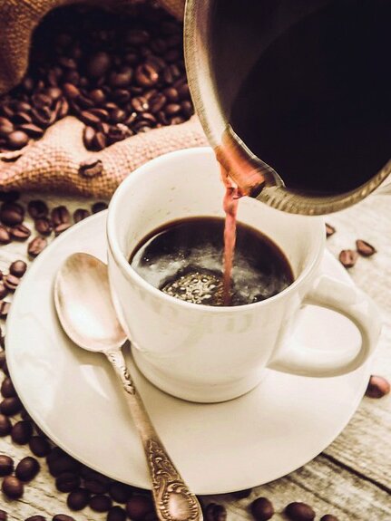 Een kopje gevuld met koffie met granen op de achtergrond