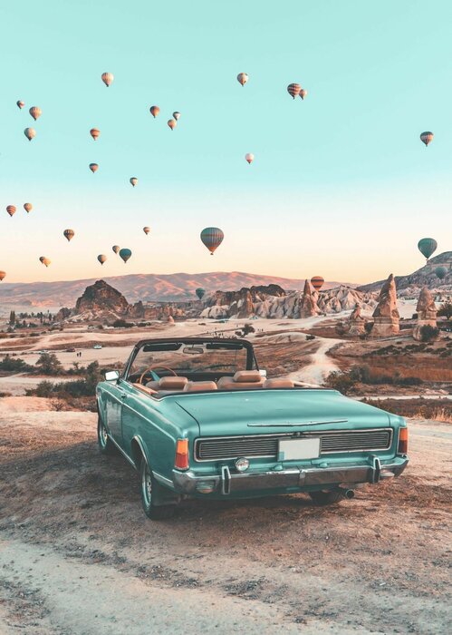 Retro car in cappadocia and balloons in the sky picturesque landscape